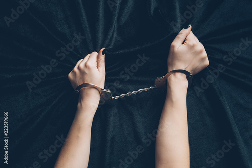 cropped shot of female hands in handcuffs holding black fabric photo