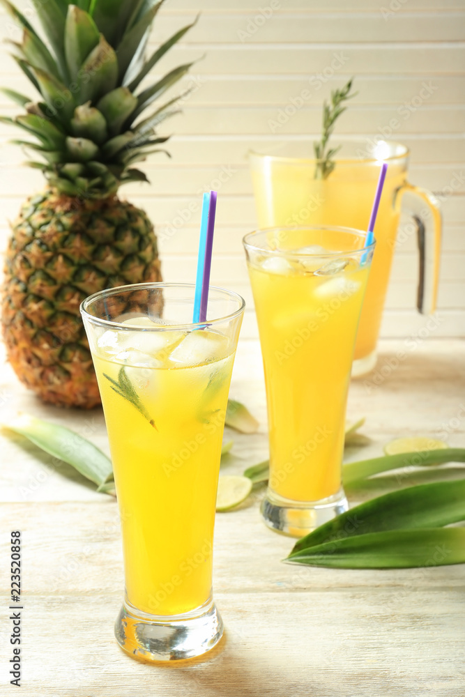 Tasty fresh cocktails with pineapple in glass on light wooden background Tasty fresh cocktails with pineapple in glass on light wooden background