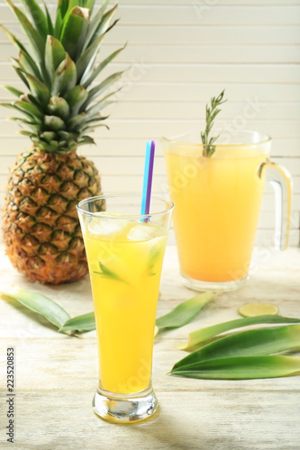 Icy fresh cocktail with pineapple in glass on light wooden background