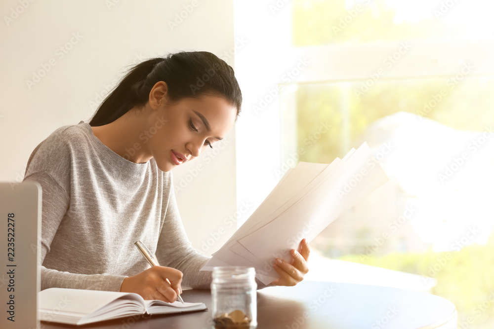 Young woman working with financial documents at table Young woman working with financial documents at table
