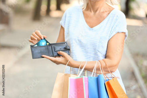 Mature woman with credit card and shopping bags outdoors