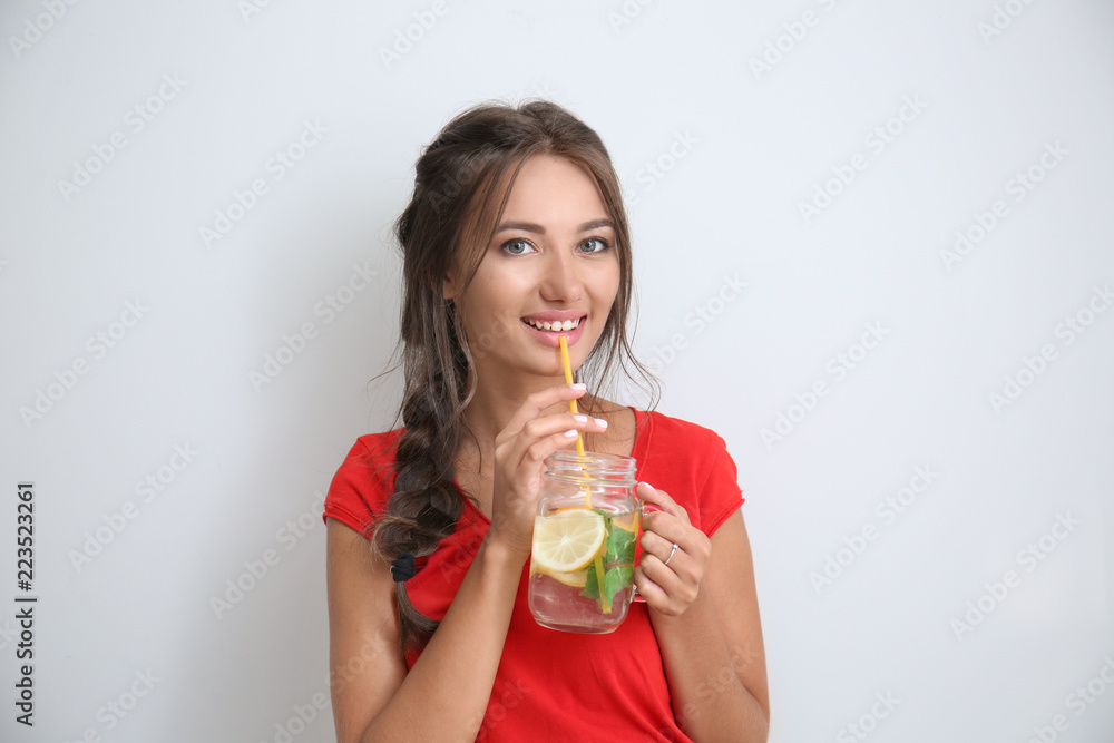 Young woman with mason jar of fresh lemonade on light background Young woman with mason jar of fresh lemonade on light background