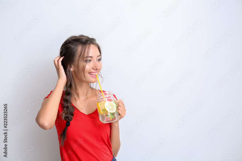 Young woman with mason jar of fresh lemonade on light background Young woman with mason jar of fresh lemonade on light background