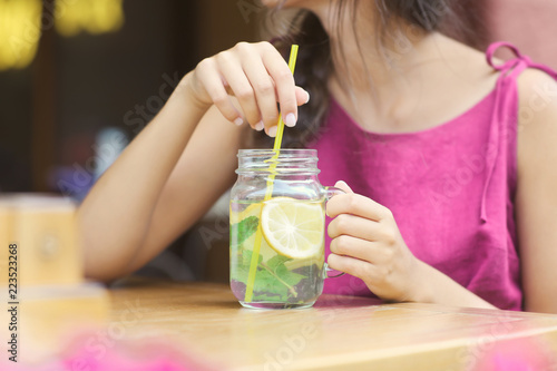 Young woman drinking fresh lemonade in cafe