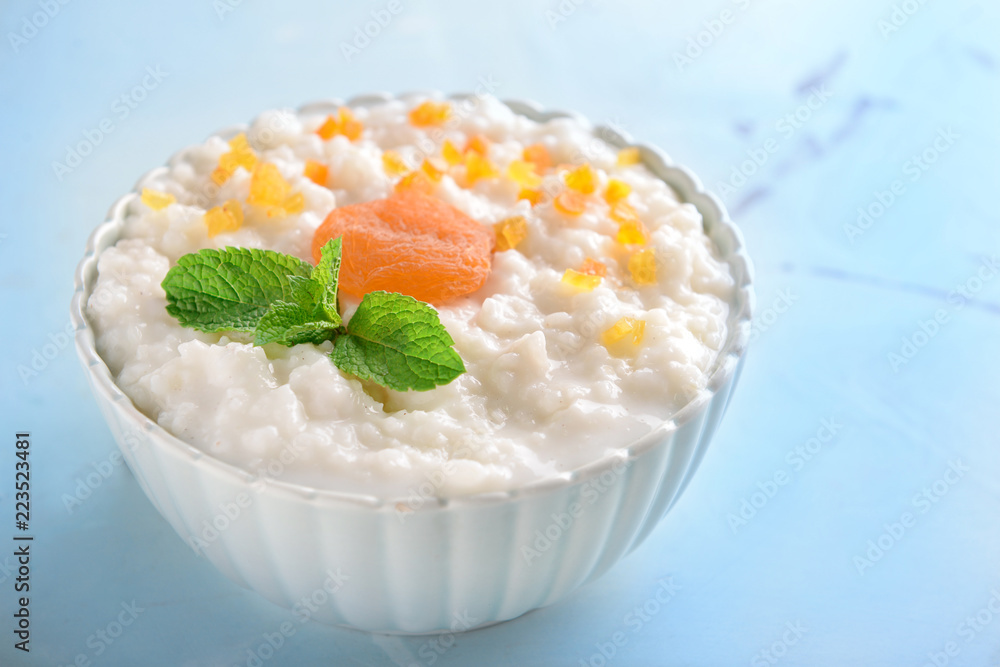 Bowl with delicious rice pudding and dry apricots on color background Bowl with delicious rice pudding and dry apricots on color background