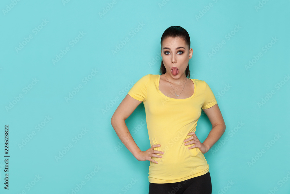 Young Woman In Yellow Shirt Is Sticking Out Tongue Young Woman In Yellow Shirt Is Sticking Out Tongue