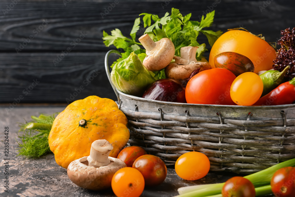 Basket with various fresh vegetables on dark table Basket with various fresh vegetables on dark table