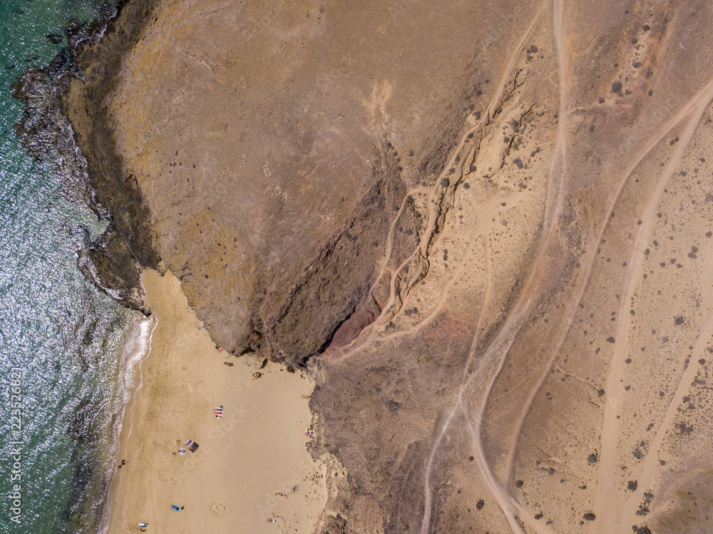Vista aerea delle coste frastagliate e delle spiagge di Lanzarote, Spagna, Canarie. Strade e sentieri sterrati. Bagnanti in spiaggia e nell’Oceano Atlantico. Papagayo