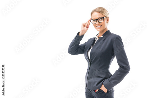 beautiful young businesswoman in suit looking at camera through eyeglasses isolated on white