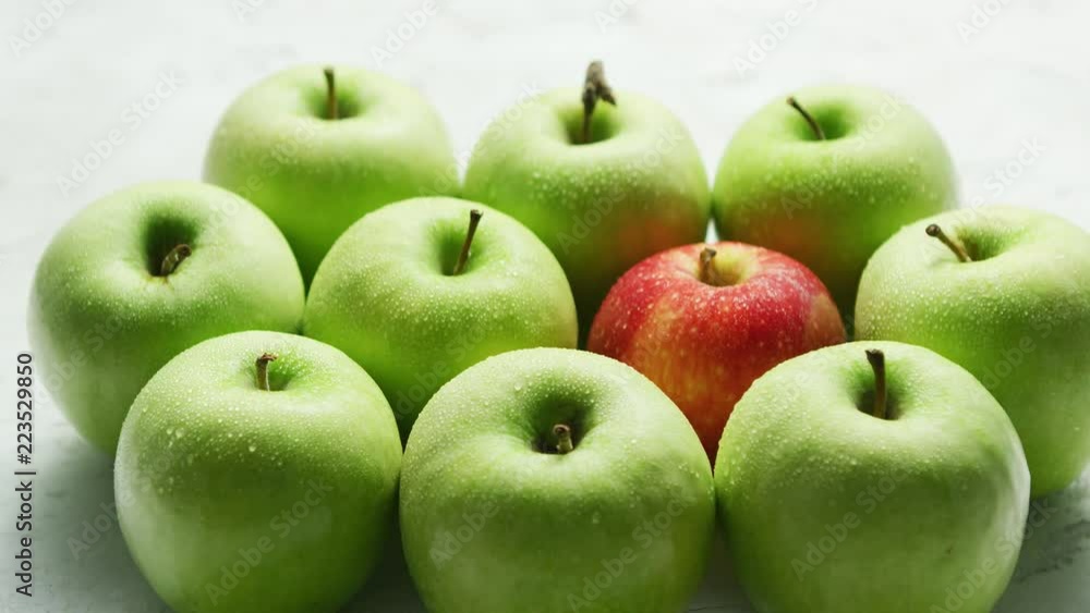 Composition of ripe and juicy green apples with one red in middle on table in daylight Composition of ripe and juicy green apples with one red in middle on table in daylight