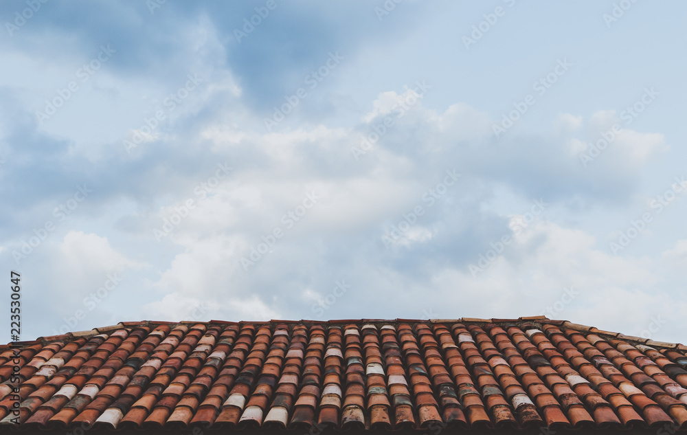 Red tiled roof under blue cloudy sky