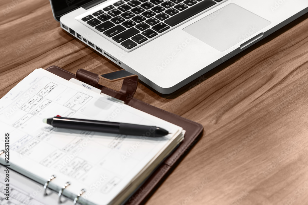 Office desktop. On the desk is a laptop, a notebook with notes and a ballpoint pen. Office desktop. On the desk is a laptop, a notebook with notes and a ballpoint pen.