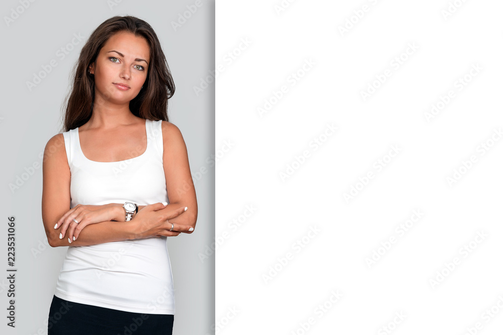 Attractive young fit woman on grey studio background. Casual woman crossed arm looking healthy and confident in white tank top. Free copyspace for text. Attractive young fit woman on grey studio background. Casual woman crossed arm looking healthy and confident in white tank top. Free copyspace for text.