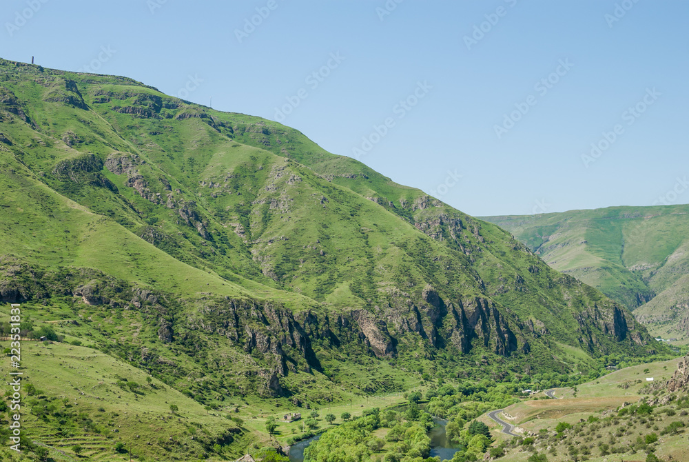 Spectacular sunny landscape in Georgia. Rocky green mountains and deep blue sky. Grass covering the hills