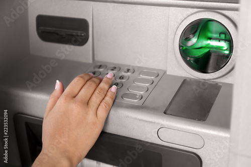 Woman entering PIN code at cash machine, closeup