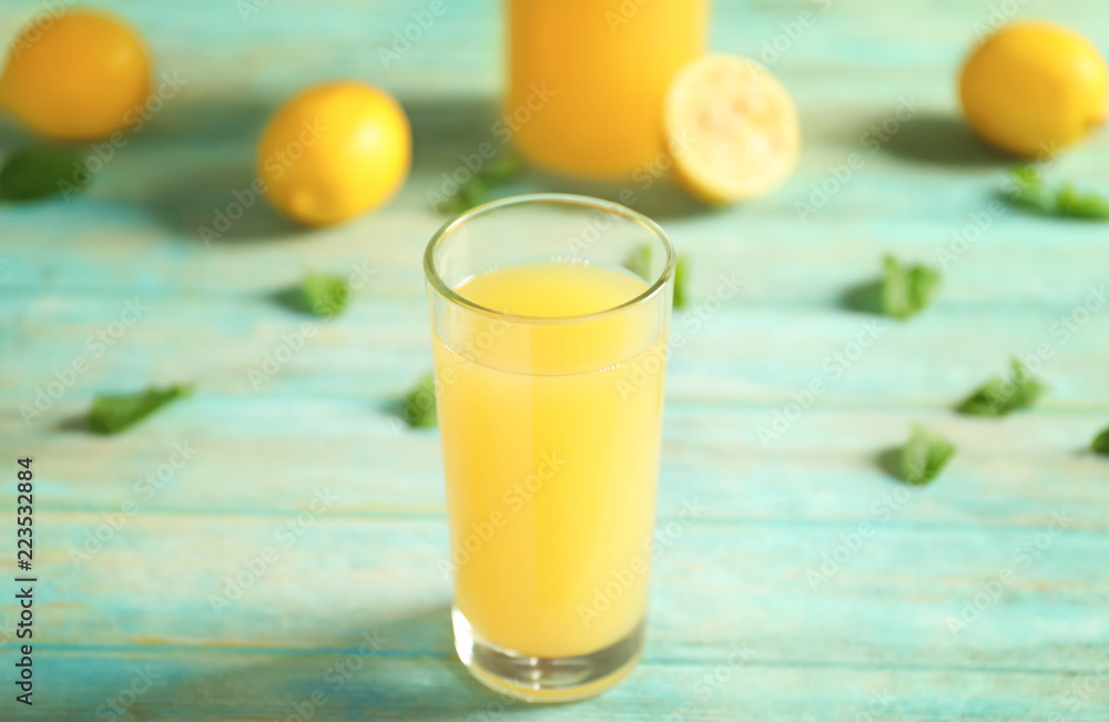Fototapeta premium Glass of fresh lemon juice on light wooden table