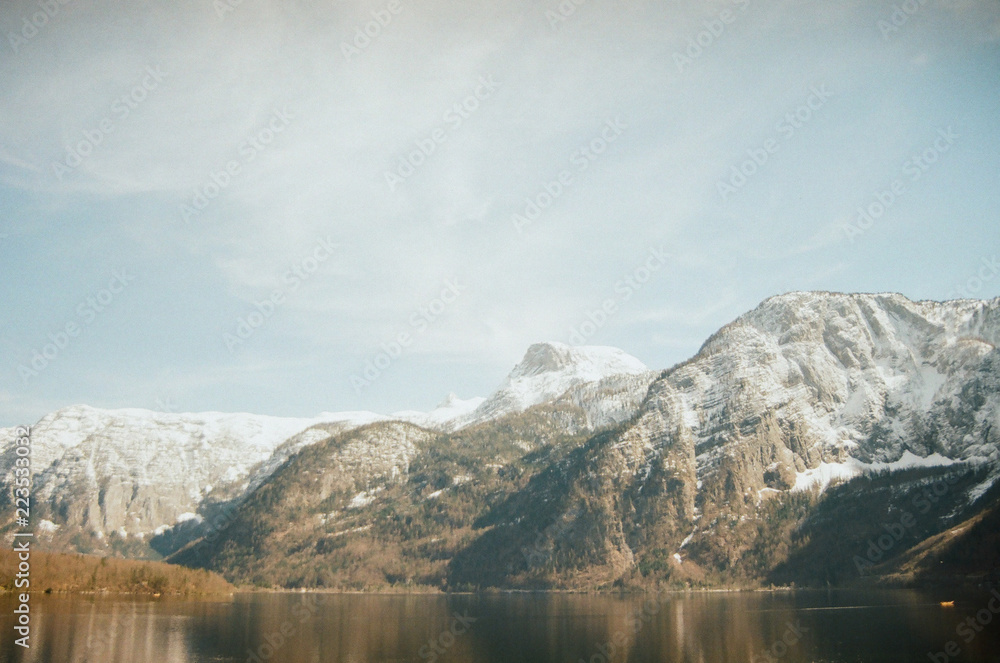 Beautiful Alpine mountains on the other side of the lake near Hallstatt. White summits beneath blue skies. View from the lakeside. Film photography