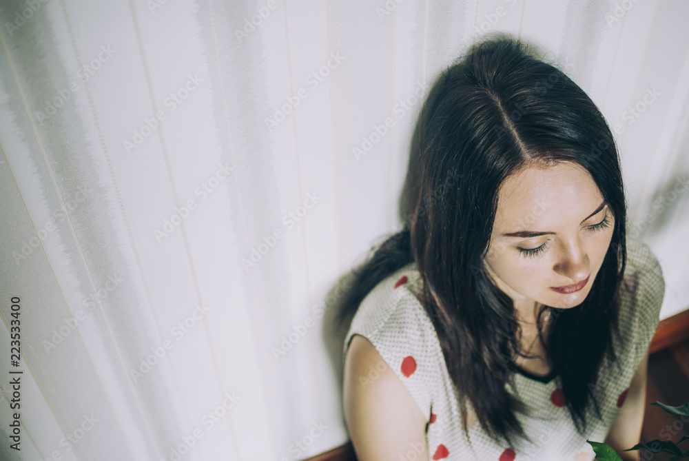 Pretty brunette girl sitting on the floor of the living room with her eyes closed and dreaming of something. Cozy leisure atmosphere at home. Pretty brunette girl sitting on the floor of the living room with her eyes closed and dreaming of something. Cozy leisure atmosphere at home.