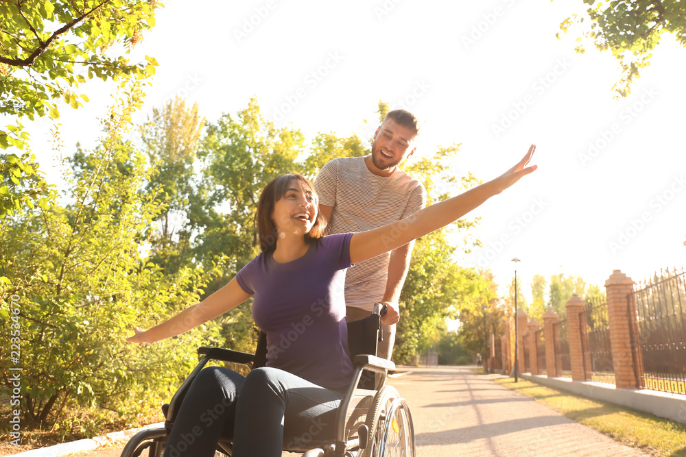 © Pixel-Shot - Happy young woman in wheelchair and her husband outdoors