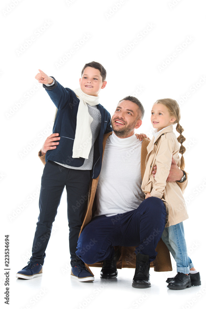 Fototapeta premium stylish father hugging kids in autumn outfit, boy showing something isolated on white