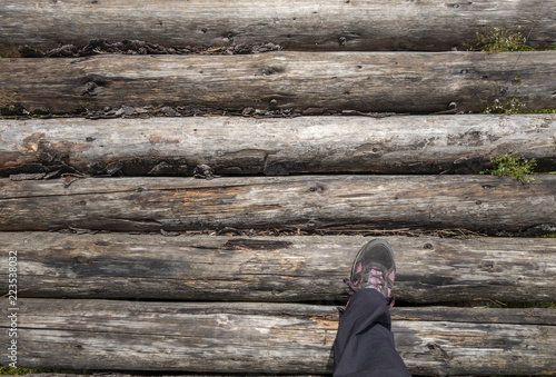 Legs with mountain shoes and black pants on wooden bridge in Bucegi National Park, Romania, summer day