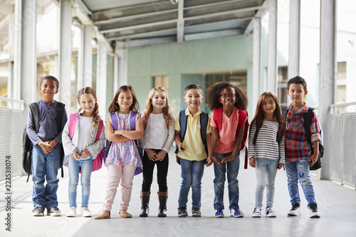 Behang Elementary school kids stand in corridor looking at camera