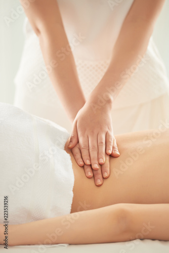 Unrecognizable woman putting pressure on loin of female client during massage session in spa salon