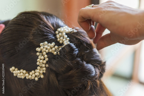 hairdresser takes a bride's hairstyle on her wedding day.black hair of the bride and white decoration on her head. 