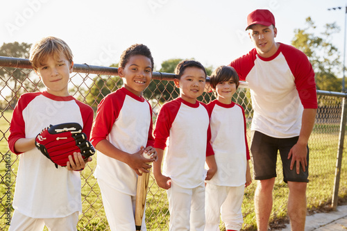 Cuadro en lienzo Coach and young boys in a baseball team looking to camera