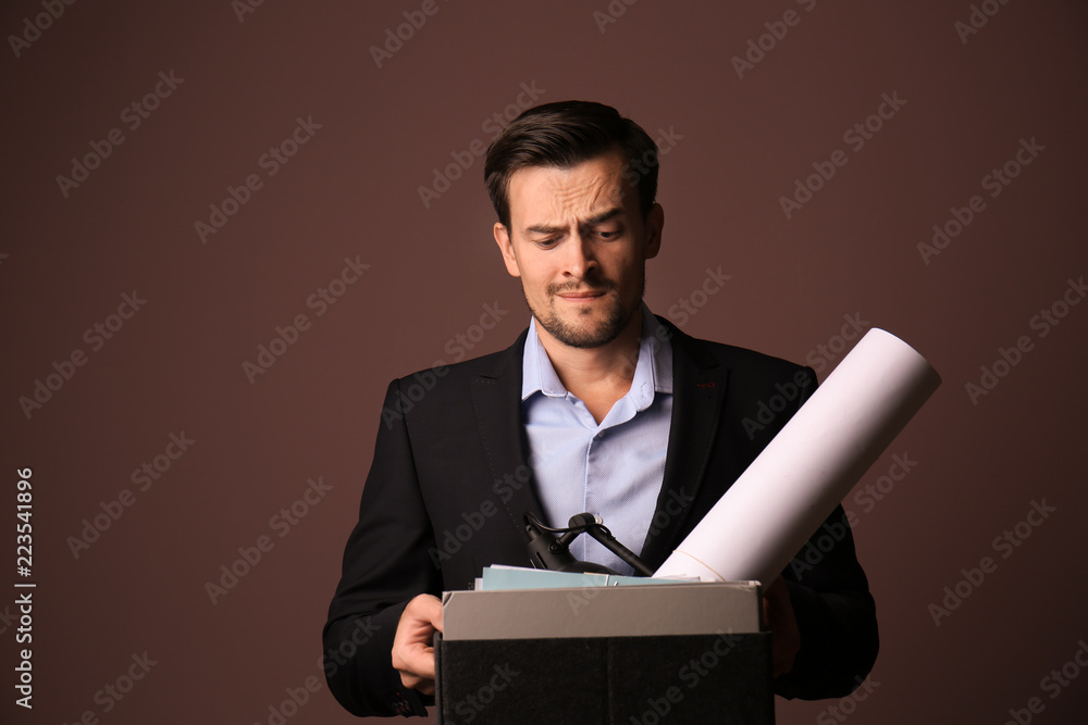 Emotional fired businessman with personal stuff on color background Emotional fired businessman with personal stuff on color background