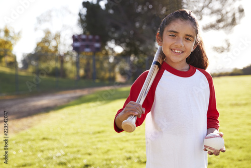 Wall Mural Young Hispanic girl with baseball and bat smiling to camera