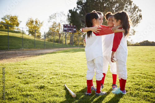 Wall Mural Schoolgirl baseball team talking in team huddle before game