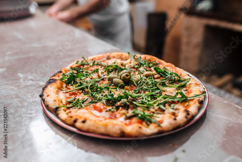 Delicious pizza with arugula and olives.