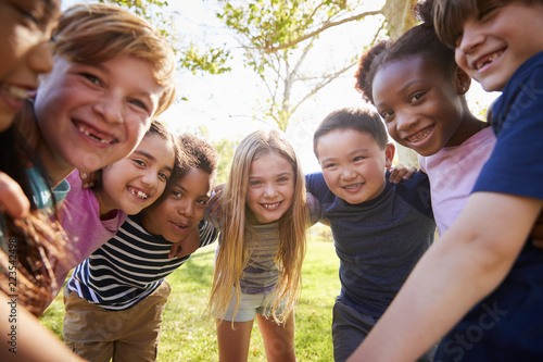 Tableau sur toile Group of smiling schoolchildren lean in to camera embracing