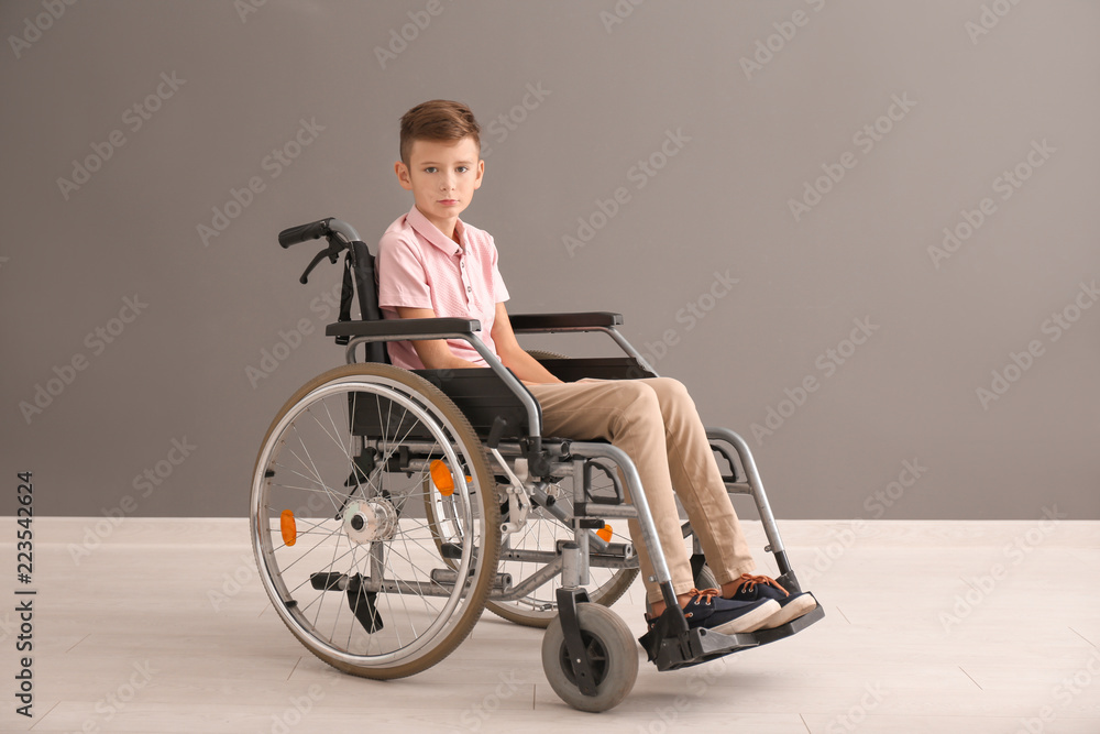 Boy in wheelchair against grey wall Boy in wheelchair against grey wall