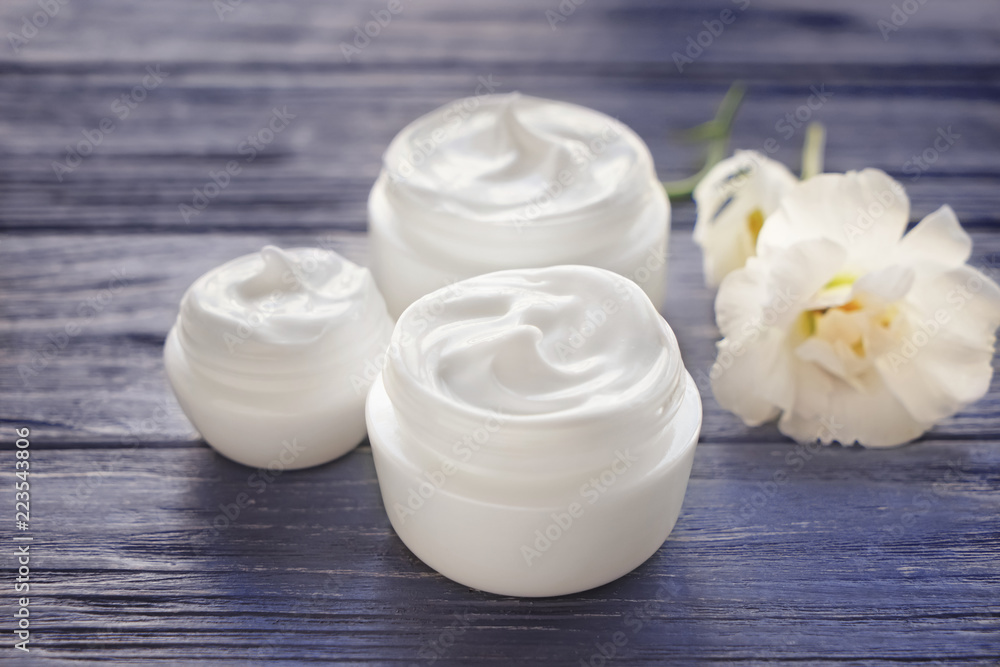 Jars with body cream on wooden table Jars with body cream on wooden table
