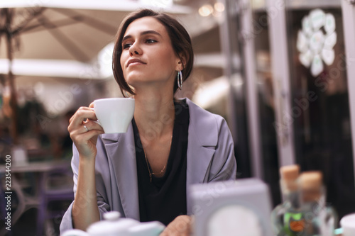 Attractive brunette bussines woman with tail drinking coffee or tea in restaurant. cofee break photo