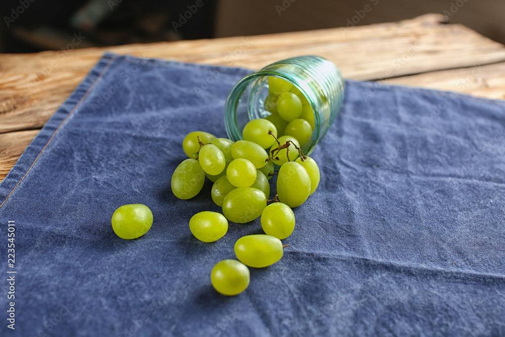 Overturned glass with scattered grapes on table Overturned glass with scattered grapes on table