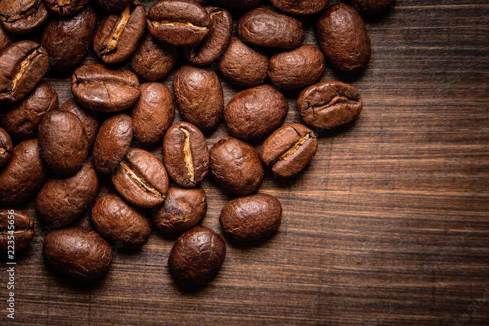 Naklejka premium coffee beans on wooden background and empty space