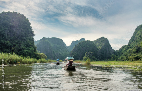Ancient boating with vietnamese using foot paddle and view limestone mountain