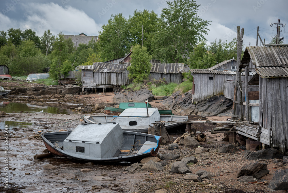 Low tide. Old boat on the background of wooden houses. Low tide. Old boat on the background of wooden houses.
