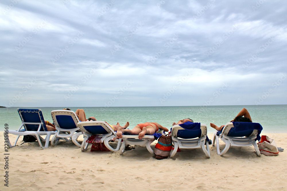 Unrecognizable adults sunbathing on the beach, shallow focus.