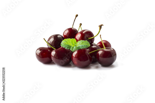 Fresh red cherries lay on white isolated background. Ripe cherry with a leaf of mint on a white background. Cherries with copy space for text.