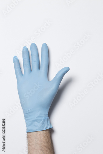 Human hand with blue glove on a light background