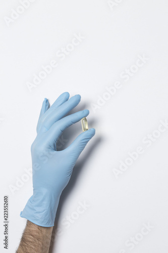 Hand in medical glove with pills on white background © Alyona