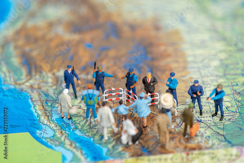 Foto Miniature toy people concept US border patrols against a group of migrant from M