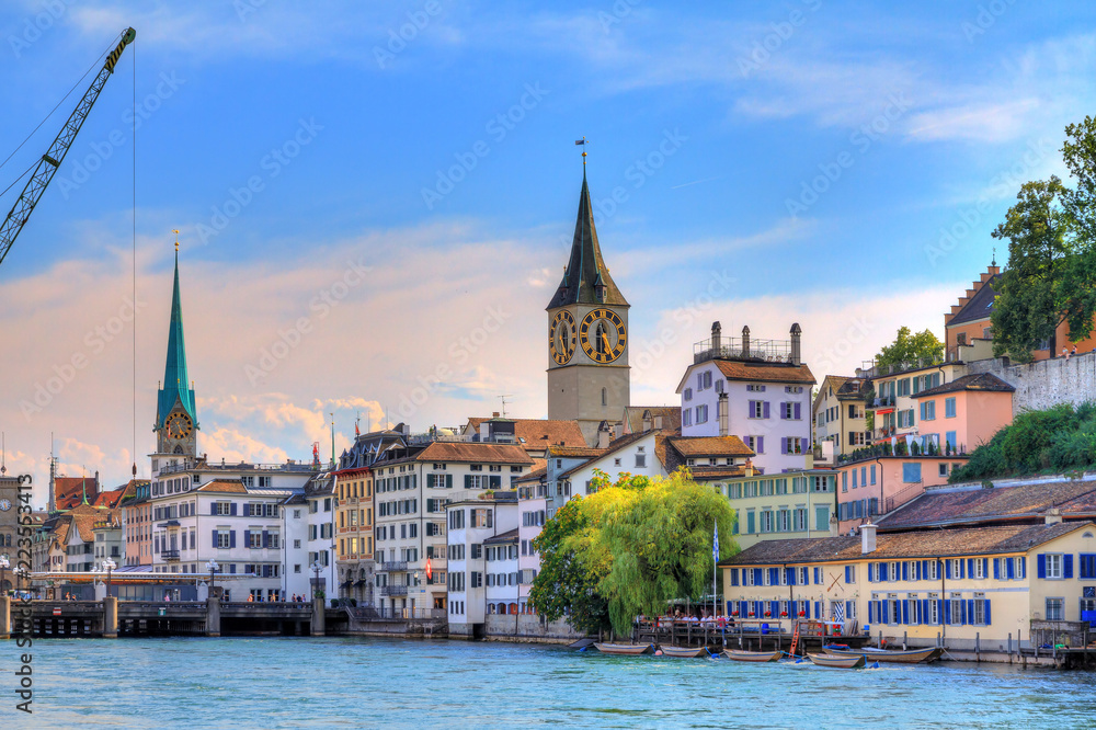 Beautiful summer cityscape of the city Zurich, Switzerland, with the big crane at the river Limmat and the Fraumünster and St. Peter Churches
