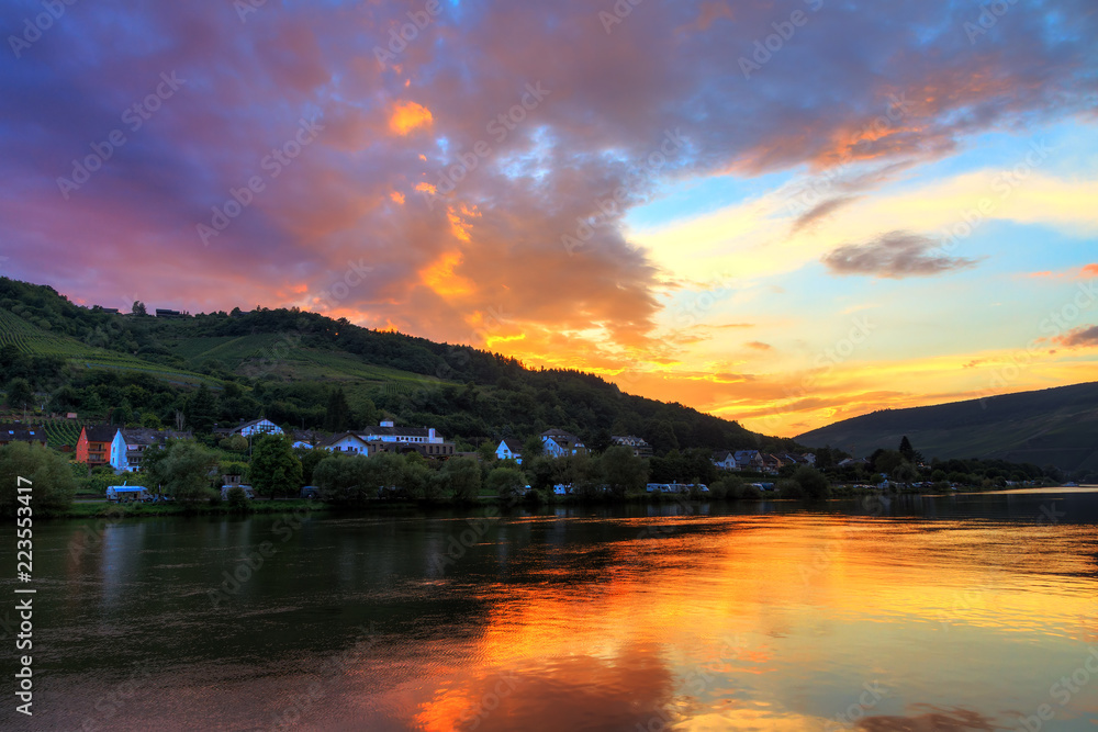 Beautiful vibrant sunset view of the river Moselle at the small wine growing town Zell (an der Mosel) with hills full of grape vines
