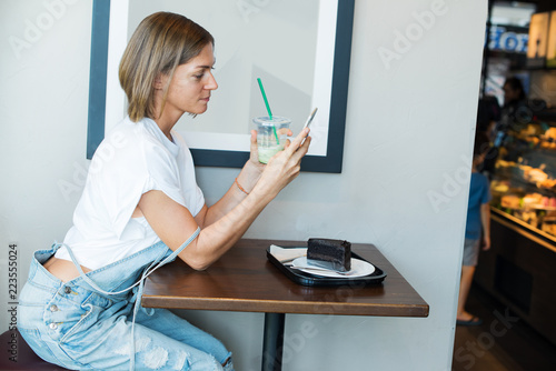 young woman wearing overalls tshirt table cafe