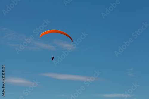 a man on a paraglider soars in the sky